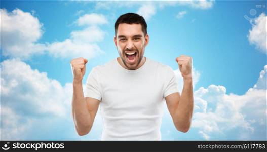 emotion, success, gesture and people concept - young man celebrating victory over blue sky and clouds background