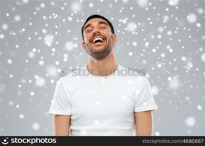 emotion, winter, christmas and people concept - laughing man over snow on gray background