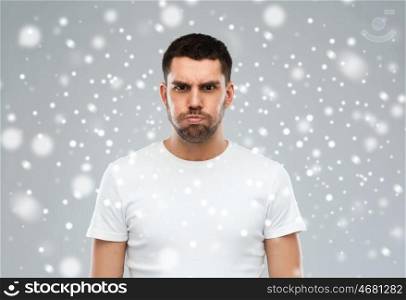 emotion, winter, christmas and people concept - man with funny angry face over snow on gray background