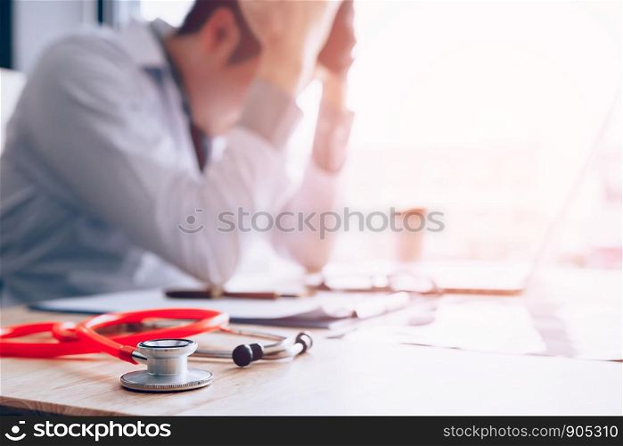 Emotion with young man doctor being exhausted and holding hands on head.