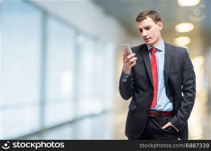 Emotional businessman with phone in hand in office