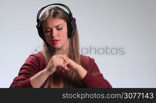 Emotional hipster girl with earphones listening to the music on white. Expressive brunette female enjoying music, singing song, moving groovily to the beat, gesturing, fooling around and expressing her crazy mood and emotions.