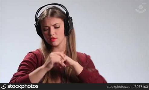 Emotional hipster girl with earphones listening to the music on white. Expressive brunette female enjoying music, singing song, moving groovily to the beat, gesturing, fooling around and expressing her crazy mood and emotions.
