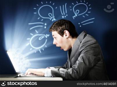Emotional man using laptop. Young man looking in laptop screen with shock