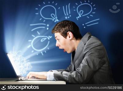 Emotional man using laptop. Young man looking in laptop screen with shock