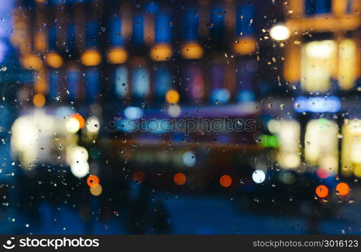 Emotional melancholic abstract background with defocused lights bokeh in London, UK behind rain drops in window glass - Focus on few drops due to the shallow depth of field. Emotional melancholic abstract background with defocused lights bokeh in London, UK behind rain drops in window glass, Focus on few drops due to the shallow depth of field