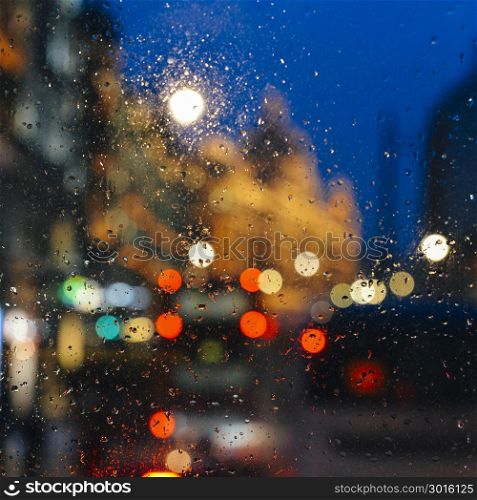 Emotional melancholic abstract background with defocused lights bokeh in London, UK behind rain drops in window glass - Focus on few drops due to the shallow depth of field. Emotional melancholic abstract background with defocused lights bokeh in London, UK behind rain drops in window glass, Focus on few drops due to the shallow depth of field