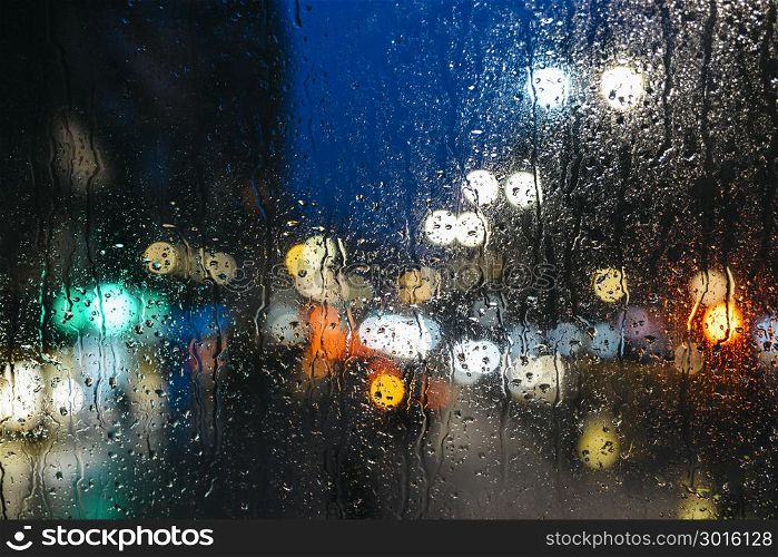 Emotional melancholic abstract background with defocused lights bokeh in London, UK behind rain drops in window glass - Focus on few drops due to the shallow depth of field. Emotional melancholic abstract background with defocused lights bokeh in London, UK behind rain drops in window glass, Focus on few drops due to the shallow depth of field