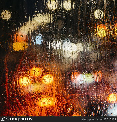 Emotional melancholic abstract background with defocused lights bokeh in London, UK behind rain drops in window glass - Focus on few drops due to the shallow depth of field. Emotional melancholic abstract background with defocused lights bokeh in London, UK behind rain drops in window glass, Focus on few drops due to the shallow depth of field