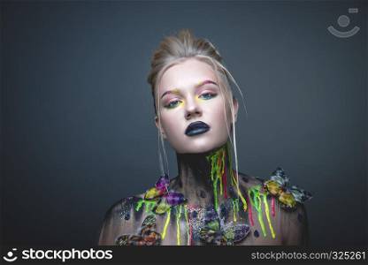 Emotional portrait of a young girl with creative makeup and colorful butterflies on her shoulders. Young girl with creative makeup with butterflies