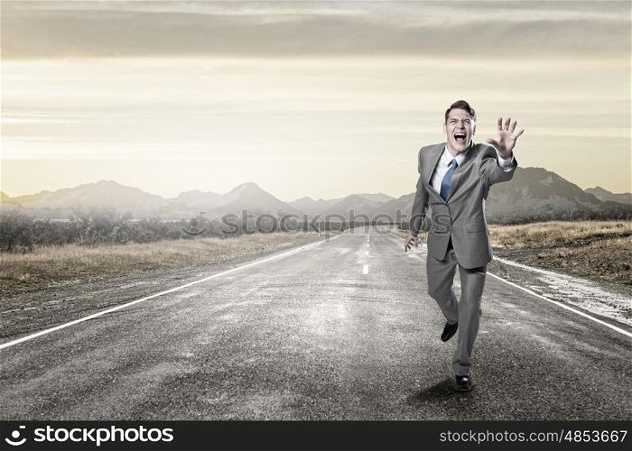 Emotional running businessman. Young screaming businessman running on asphalt road