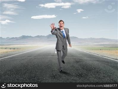 Emotional running businessman. Young screaming businessman running on asphalt road