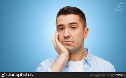 emotions and people concept - bored middle aged man face over blue background. bored middle aged man face over blue background