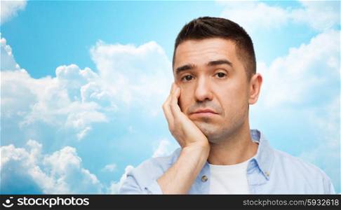 emotions and people concept - bored middle aged man face over blue sky and clouds background. bored man face over blue sky and clouds background