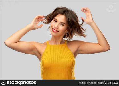 emotions and people concept - happy laughing young woman in mustard yellow top over grey background. happy laughing young woman in mustard yellow top