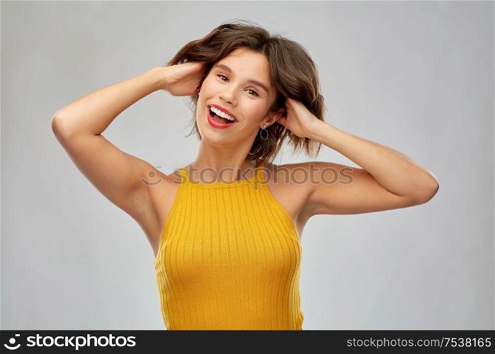 emotions and people concept - happy laughing young woman in mustard yellow top over grey background. happy laughing young woman in mustard yellow top