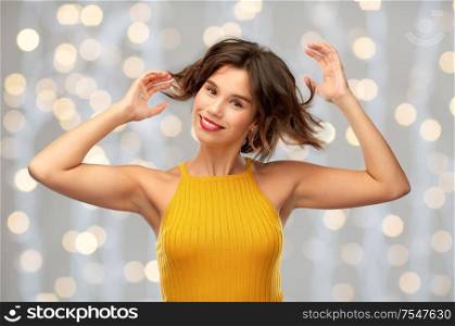 emotions and people concept - happy laughing young woman in yellow top over festive lights background. happy laughing woman in yellow top over lights