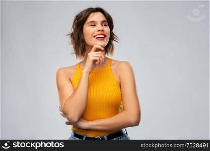emotions and people concept - happy smiling thinking young woman in mustard yellow top over grey background. happy thinking young woman in mustard yellow top