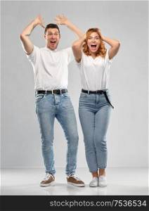 emotions and people concept - portrait of happy couple in white t-shirts celebrating success over grey background. portrait of happy couple in white t-shirts
