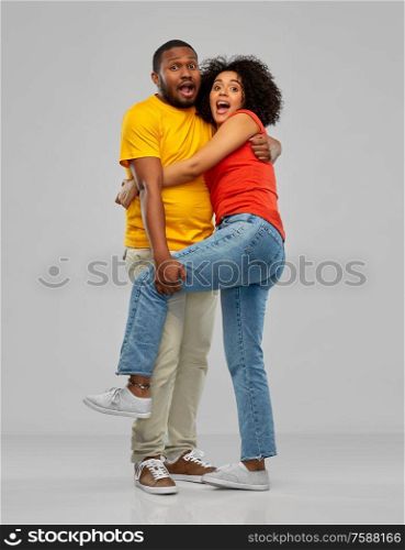 emotions and people concept - scared african american couple hugging over grey background. scared african american couple hugging