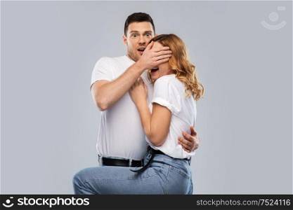 emotions and people concept - scared couple in white t-shirts over grey background. scared couple in white t-shirts