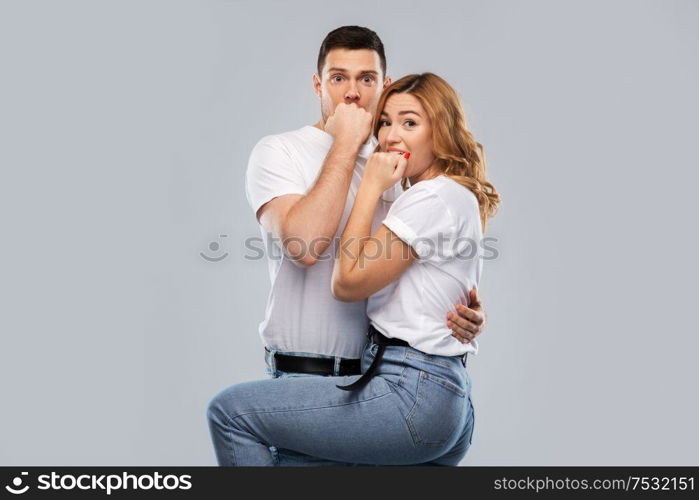 emotions and people concept - scared couple in white t-shirts over grey background. scared couple in white t-shirts