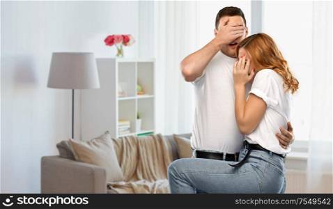 emotions and people concept - scared couple in white t-shirts over home room background. scared couple in white t-shirts at home