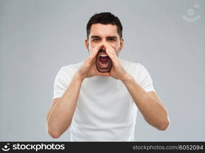 emotions, communication and people concept - angry shouting man in t-shirt over gray background