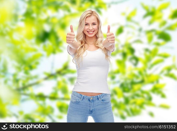 emotions, expressions, advertisement and people concept - happy smiling young woman or teenage girl in white t-shirt showing thumbs up with both hands over green natural background