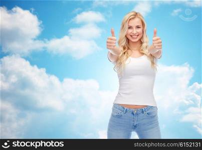 emotions, expressions, advertisement and people concept - happy smiling young woman or teenage girl in white t-shirt showing thumbs up with both hands over blue sky and clouds background