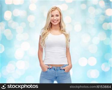 emotions, expressions, advertisement and people concept - happy smiling young woman or teenage girl in white t-shirt over blue holidays lights background