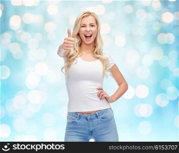 emotions, expressions, advertisement and people concept - happy smiling young woman or teenage girl in white t-shirt showing thumbs up over blue holidays lights background