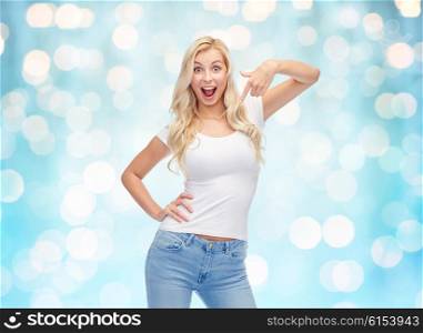 emotions, expressions, advertisement and people concept - happy smiling young woman or teenage girl in white t-shirt pointing finger to herself over blue holidays lights background