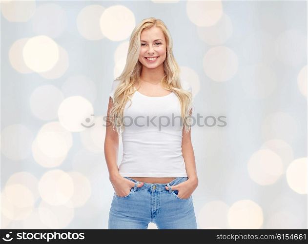 emotions, expressions, advertisement and people concept - happy smiling young woman or teenage girl in white t-shirt over holidays lights background