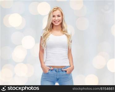 emotions, expressions, advertisement and people concept - happy smiling young woman or teenage girl in white t-shirt over holidays lights background