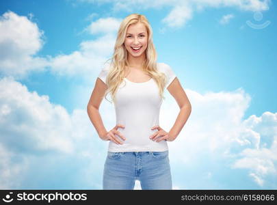 emotions, expressions, advertisement and people concept - happy smiling young woman or teenage girl in white t-shirt over blue sky and clouds background