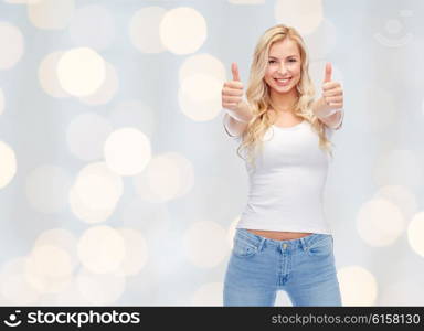 emotions, expressions, advertisement and people concept - happy smiling young woman or teenage girl in white t-shirt showing thumbs up with both hands over holidays lights background