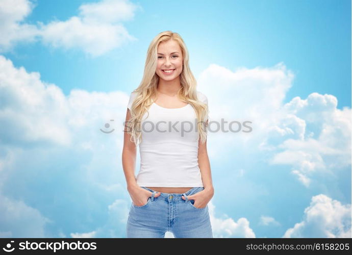 emotions, expressions, advertisement and people concept - happy smiling young woman or teenage girl in white t-shirt over blue sky and clouds background