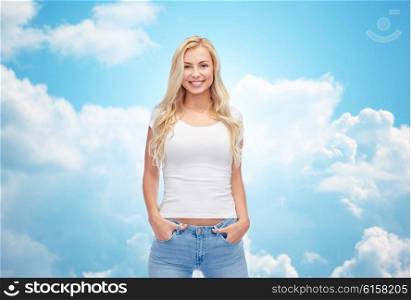 emotions, expressions, advertisement and people concept - happy smiling young woman or teenage girl in white t-shirt over blue sky and clouds background