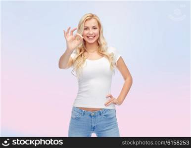 emotions, expressions, advertisement and people concept - happy smiling young woman or teenage girl in white t-shirt showing ok hand sign over rose quartz and serenity gradient background