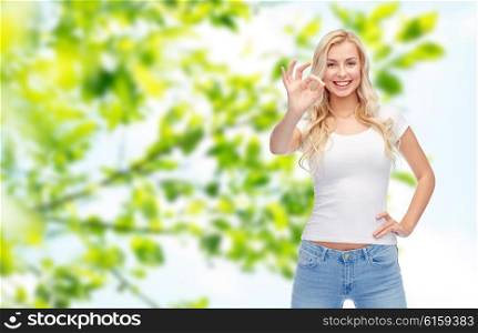emotions, expressions, advertisement and people concept - happy smiling young woman or teenage girl in white t-shirt showing ok hand sign over green natural background