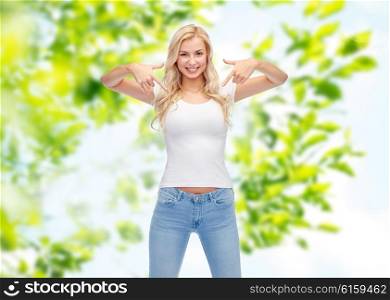 emotions, expressions, advertisement and people concept - happy smiling young woman or teenage girl in white t-shirt pointing finger to herself over green natural background