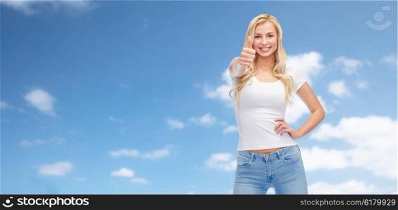 emotions, expressions, advertisement and people concept - happy smiling young woman or teenage girl in white t-shirt showing thumbs up over blue sky and clouds background