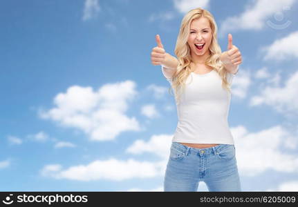 emotions, expressions, advertisement and people concept - happy smiling young woman or teenage girl in white t-shirt showing thumbs up with both hands over blue sky and clouds background