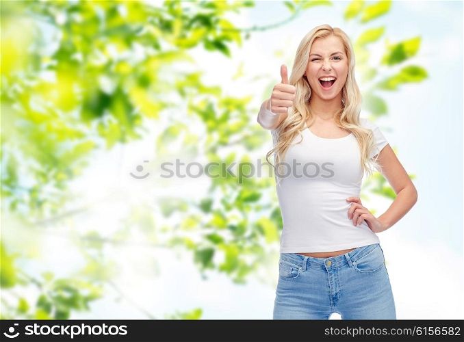 emotions, expressions, advertisement, summer and people concept - happy smiling young woman or teenage girl in white t-shirt showing thumbs up over green natural background
