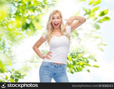 emotions, expressions, advertisement, summer and people concept - happy smiling young woman or teenage girl in white t-shirt pointing finger to herself over green natural background