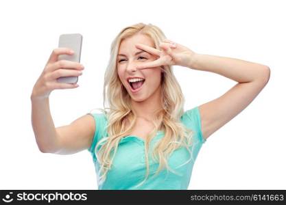 emotions, expressions and people concept - happy smiling young woman or teenage girl taking selfie with smartphone