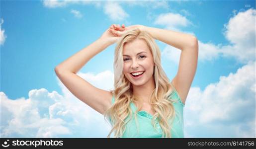 emotions, expressions and people concept - happy smiling young woman or teenage girl over blue sky and clouds background