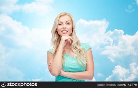 emotions, expressions and people concept - happy smiling young woman or teenage girl over blue sky and clouds background