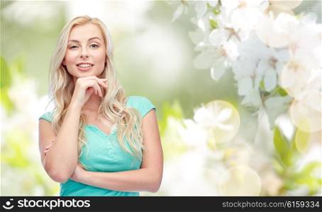 emotions, expressions and people concept - happy smiling young woman or teenage girl over natural spring cherry blossom background